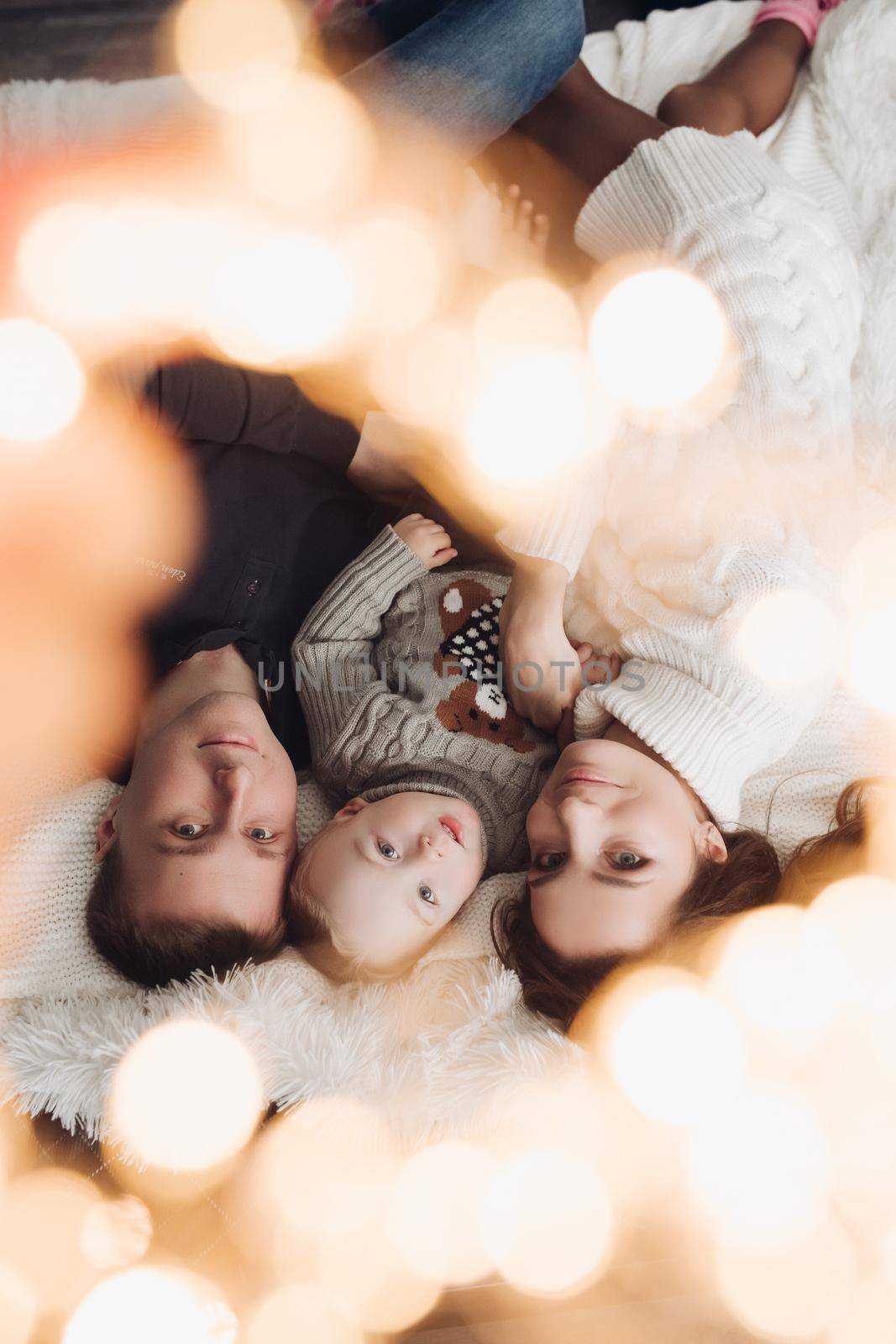Upside down photo of a lovely little family laying down together under the Christmas lights