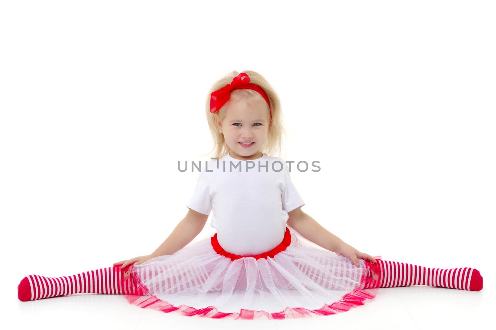 Little girl schoolgirl, performs gymnastic twine in the studio on a white background. Concept of fitness and sport and healthy lifestyle.