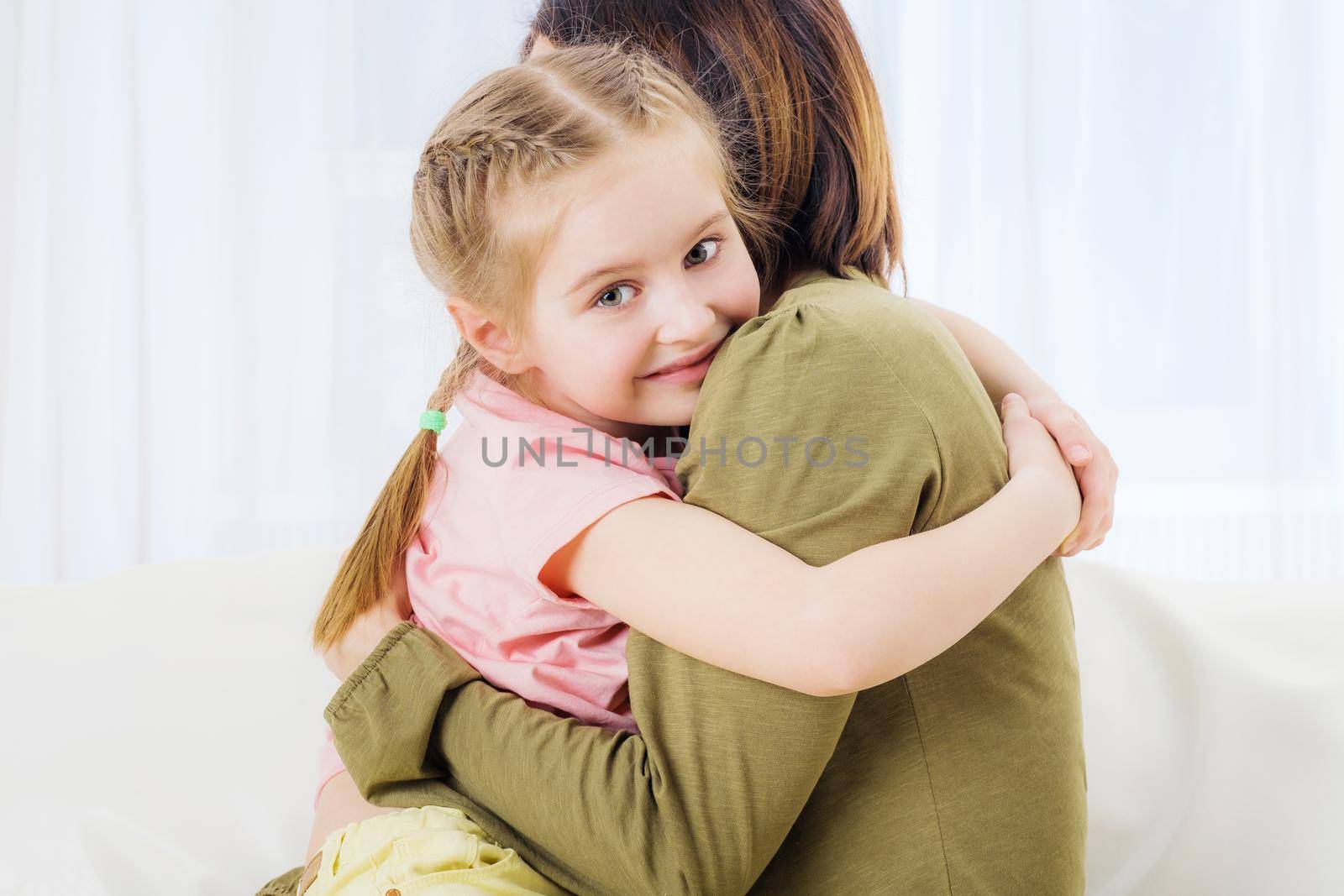 Woman and her daughter hugging on couch by GekaSkr