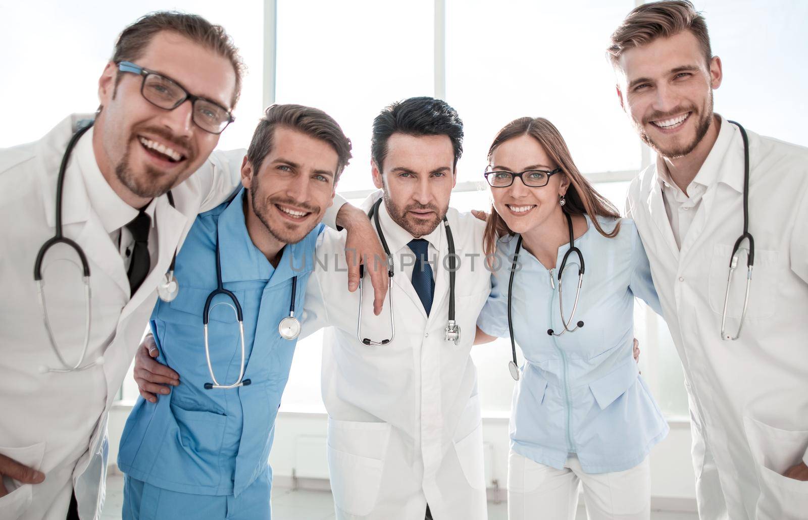 Excited happy smiling group of people in hospital, wear white lab coats