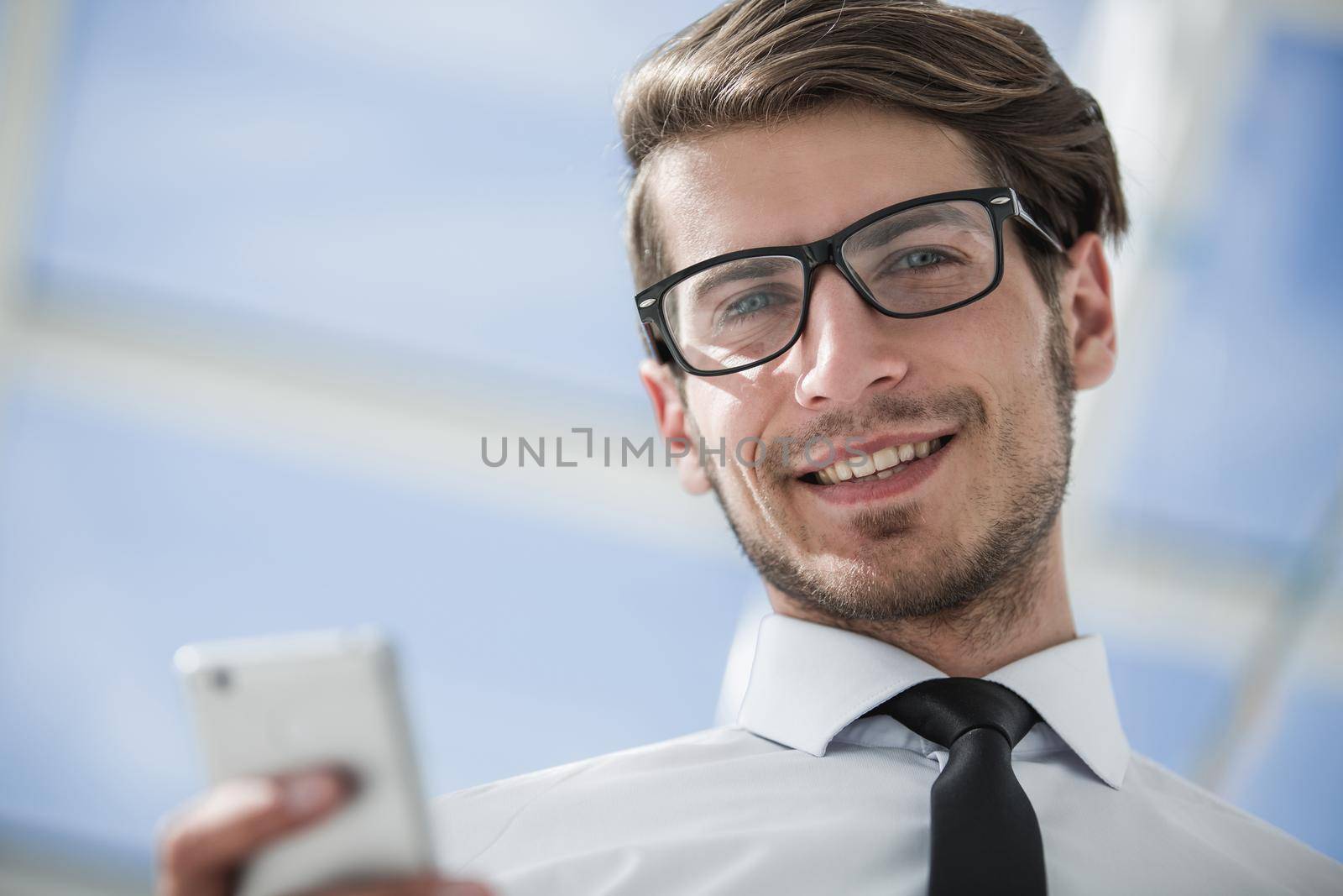 close up.confident businessman with smartphone.people and technology