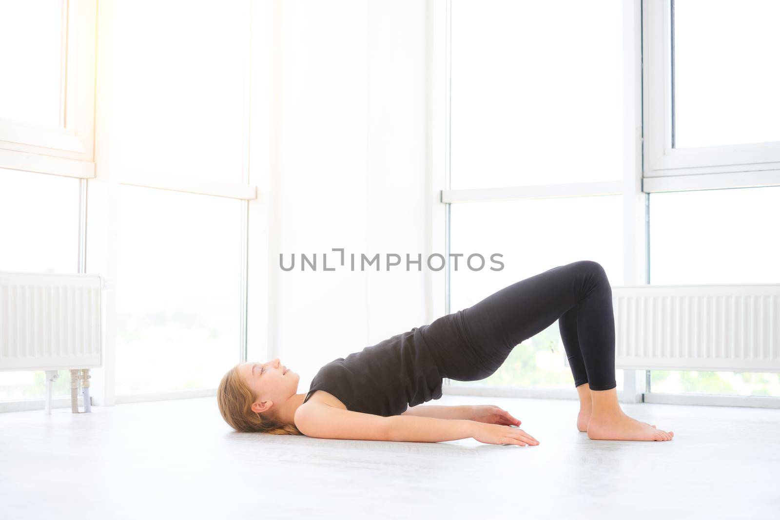Pretty young girl doing exercises on a floor in white room