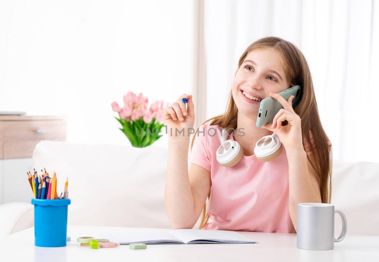 Adorable girl making calls to her school friends in free time