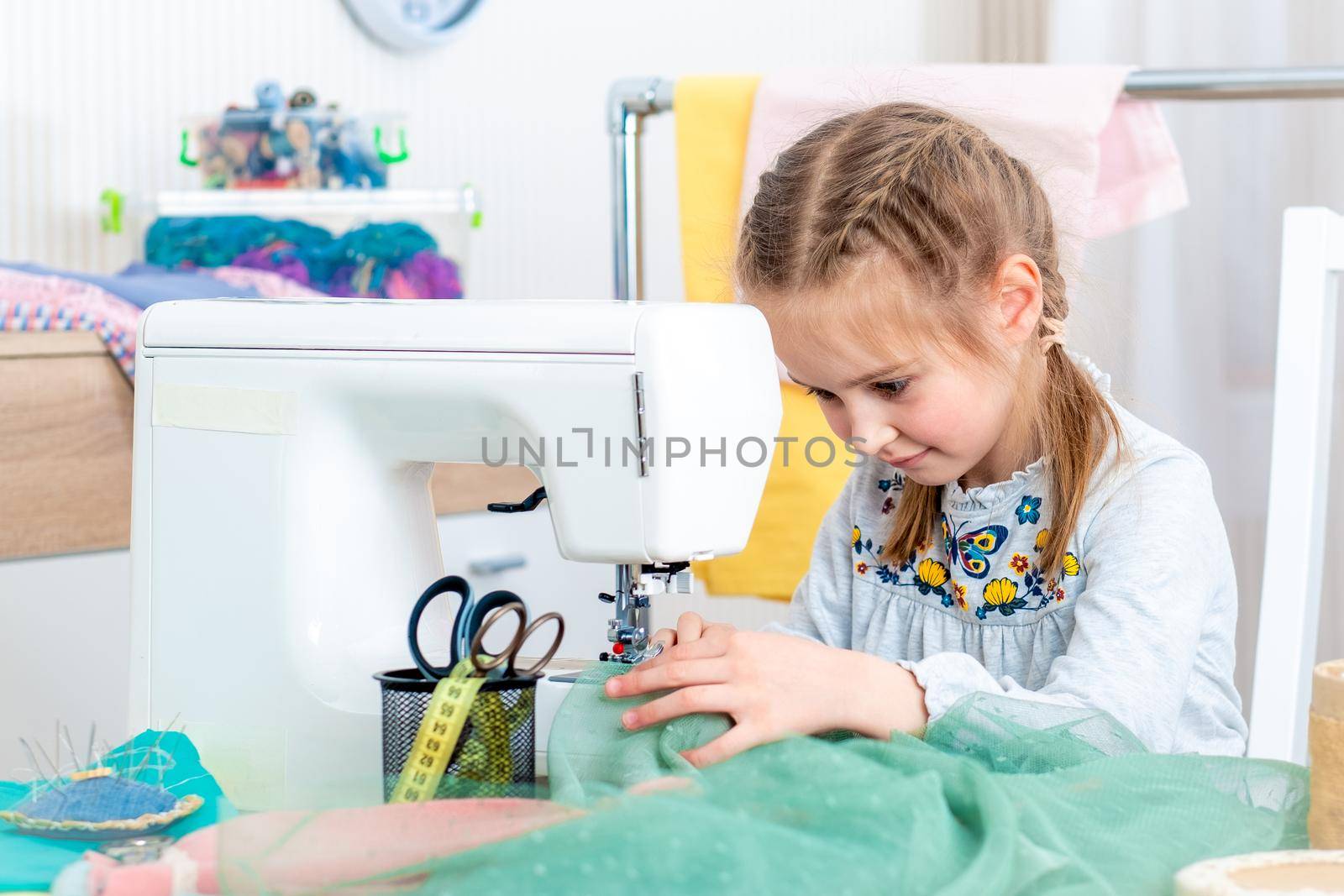 Little girl making crafts at sewing machine by GekaSkr