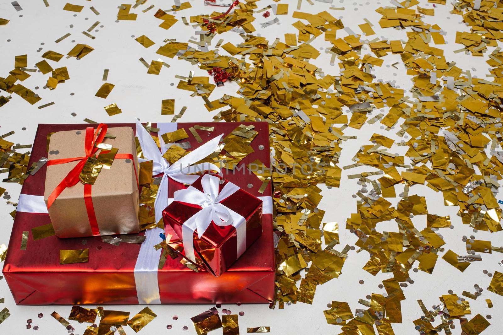 Three presents on the floor covered with golden confetti. by StudioLucky