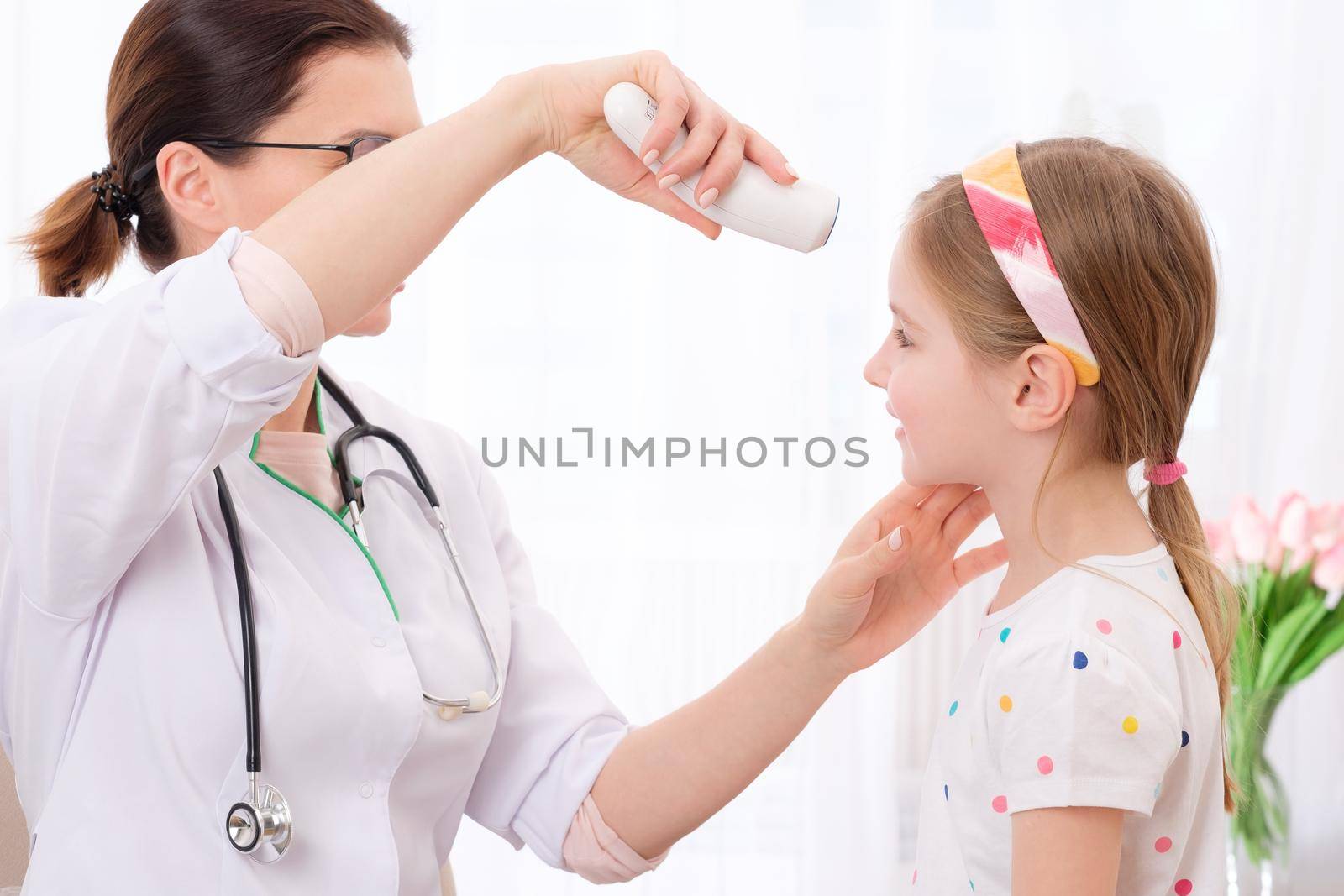 Professional doctor checking the level of adorable girls temperature with thermometer