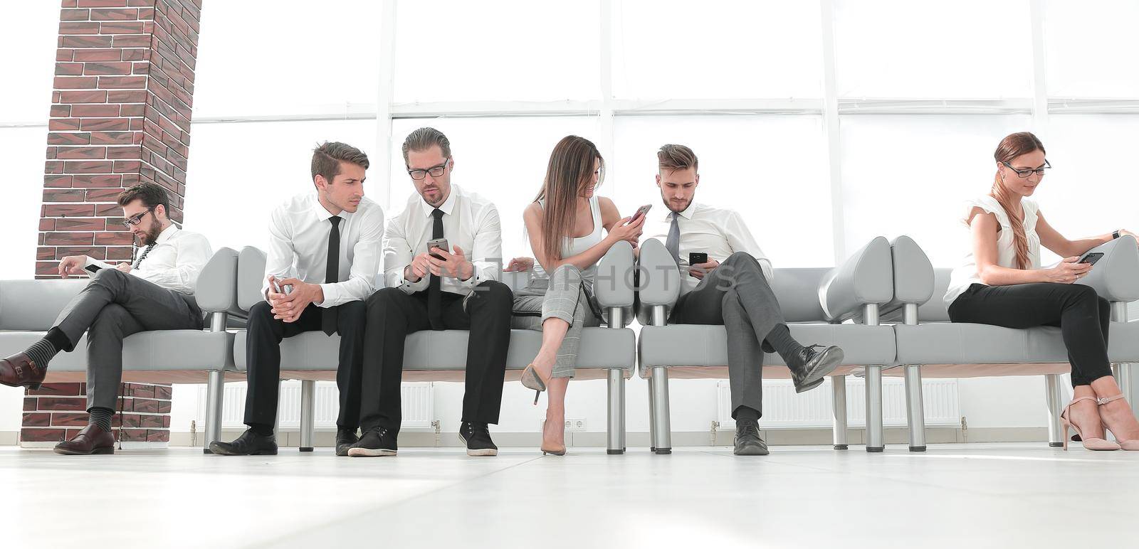 business team with mobile phones sitting in the lobby of the office by asdf