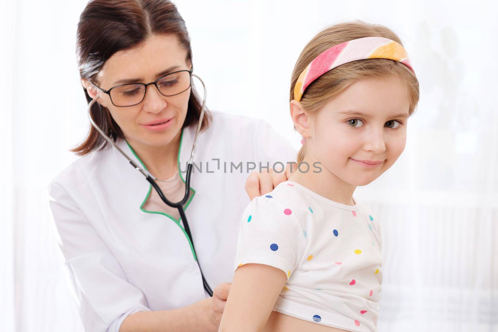 Female doctor listening to little girls internal sounds with stethoscope