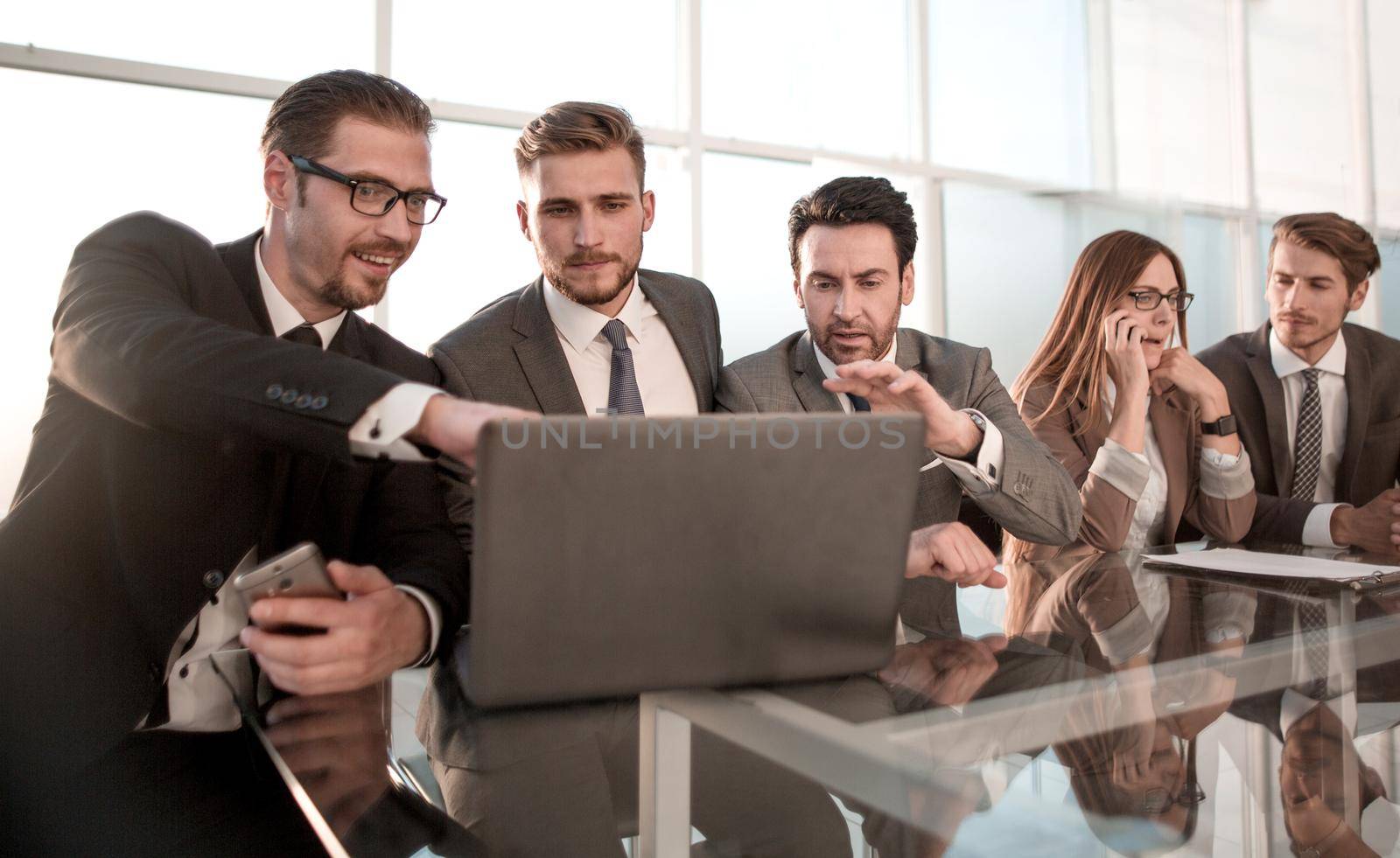 Businessmen and businessmen using laptop together, sitting in front of windows of office building
