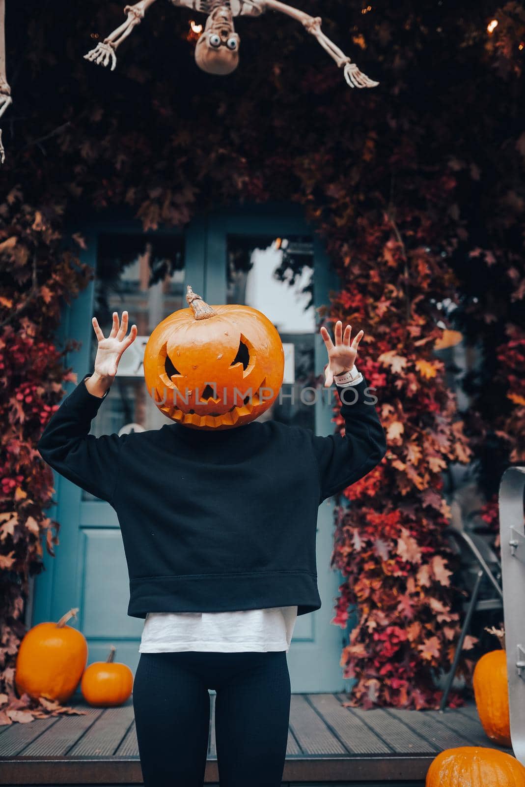 Girl with a pumpkin head scares at the camera . Halloween Concept
