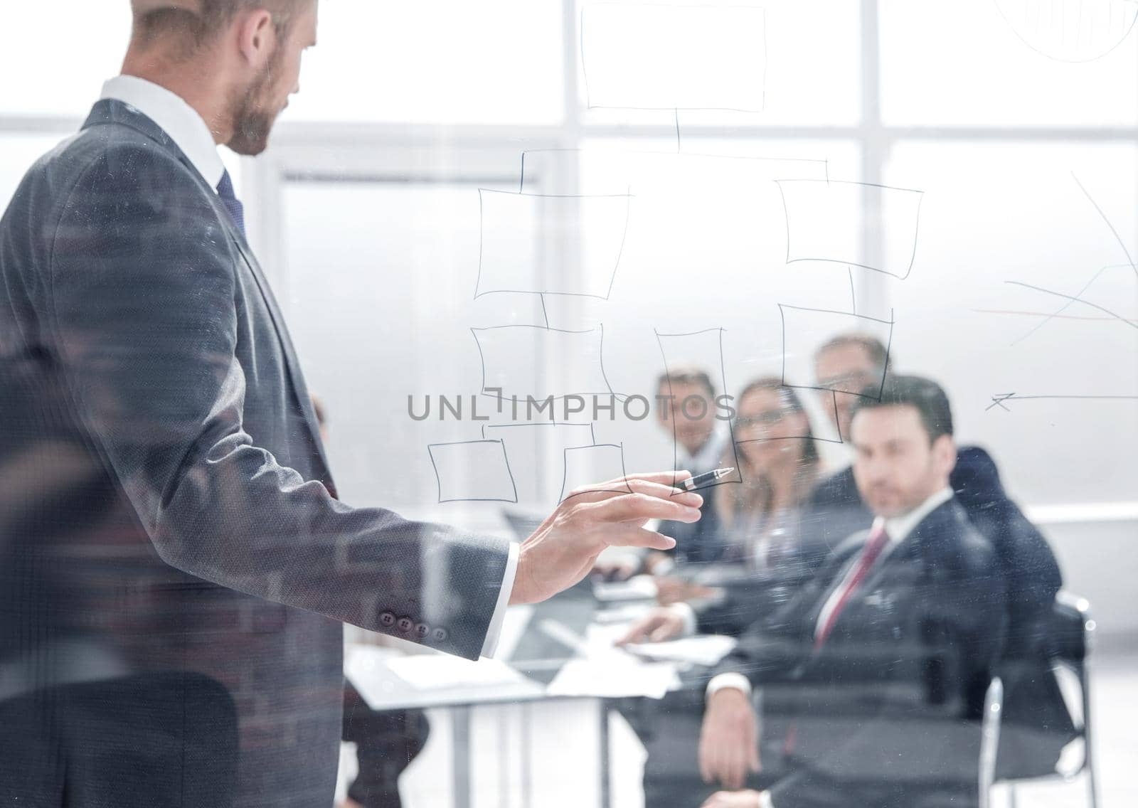 Focused caucasian business people meeting in boardroom behind glass.