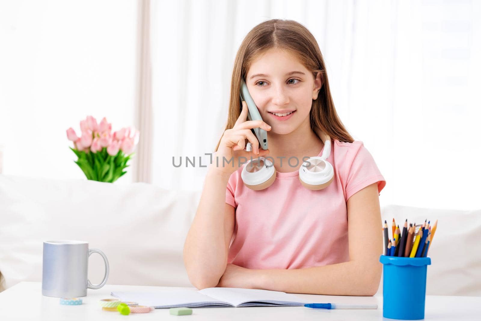 Adorable girl making calls to her school friends in free time