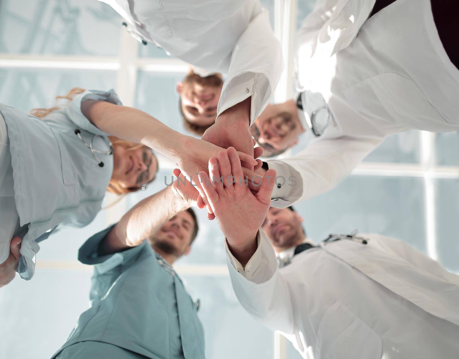 A group of doctors are holding each other's hands. They demonstrate close cooperation and friendship. They work in the hospital.