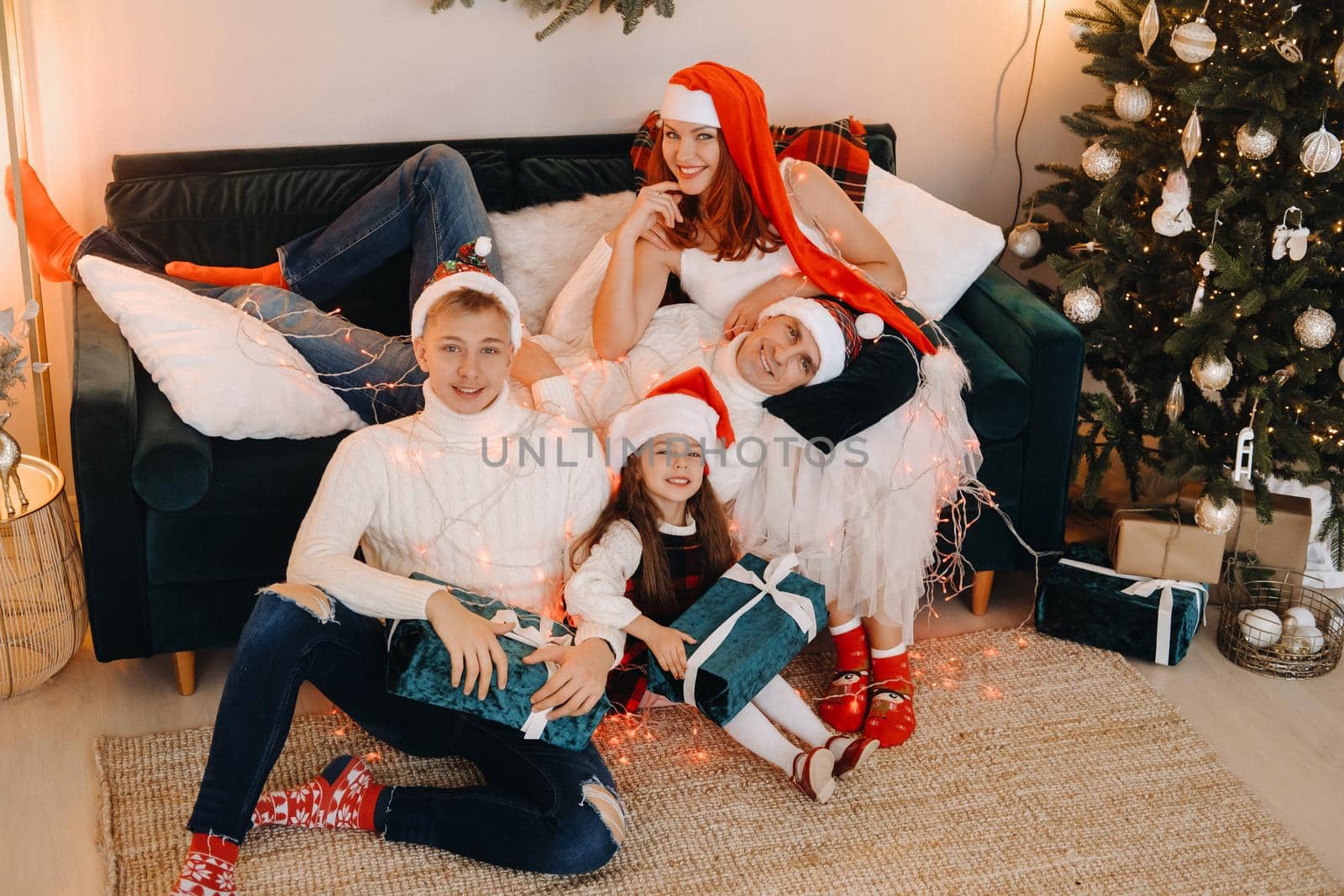 Close-up portrait of a happy family sitting on a sofa near a Christmas tree celebrating a holiday.