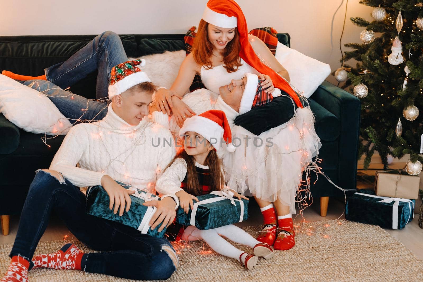 Close-up portrait of a happy family sitting on a sofa near a Christmas tree celebrating a holiday.