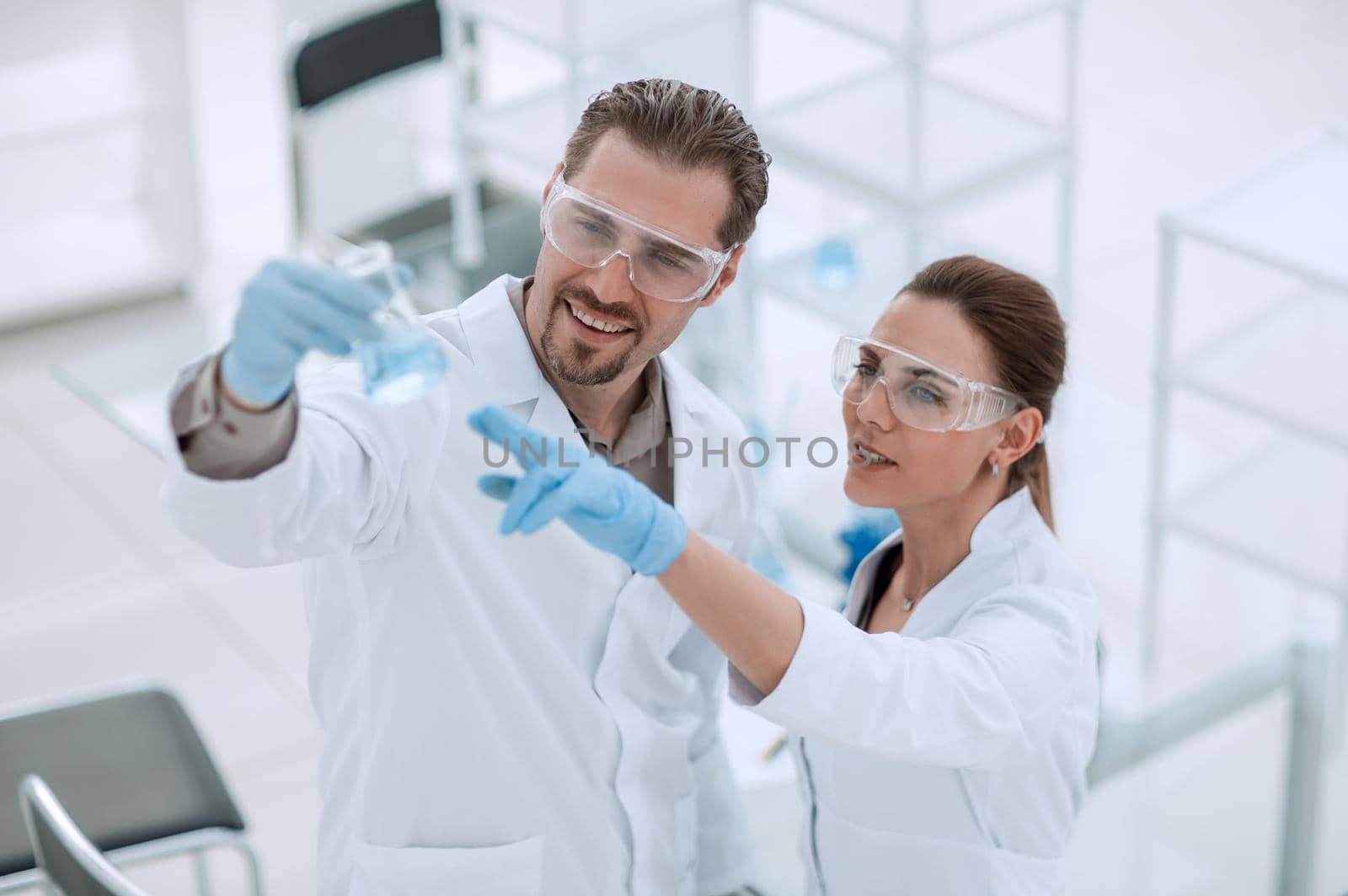 scientist and assistant look at the liquid in the flask.photo with copy space