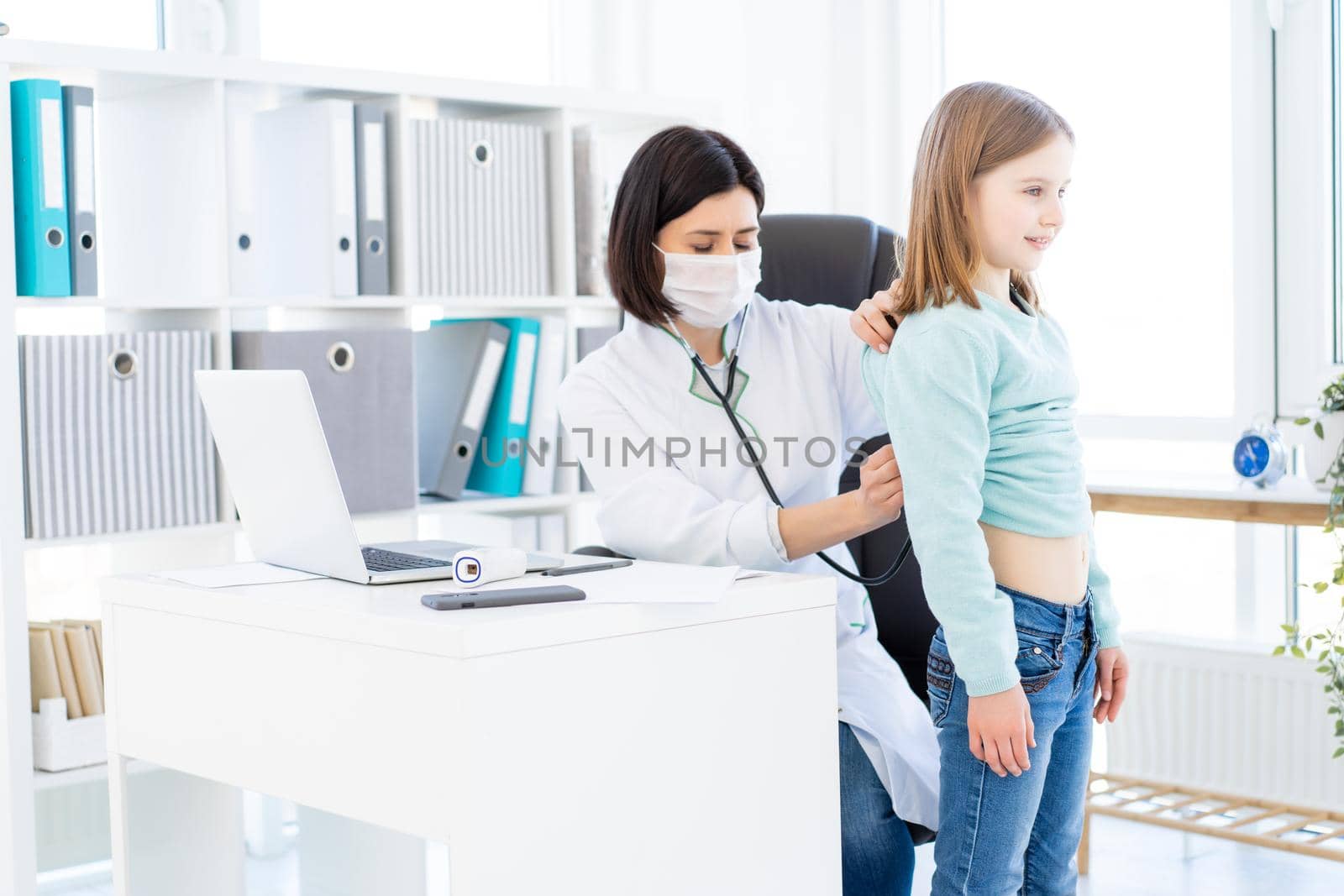Nice doctor listening to little girl with phonendoscope