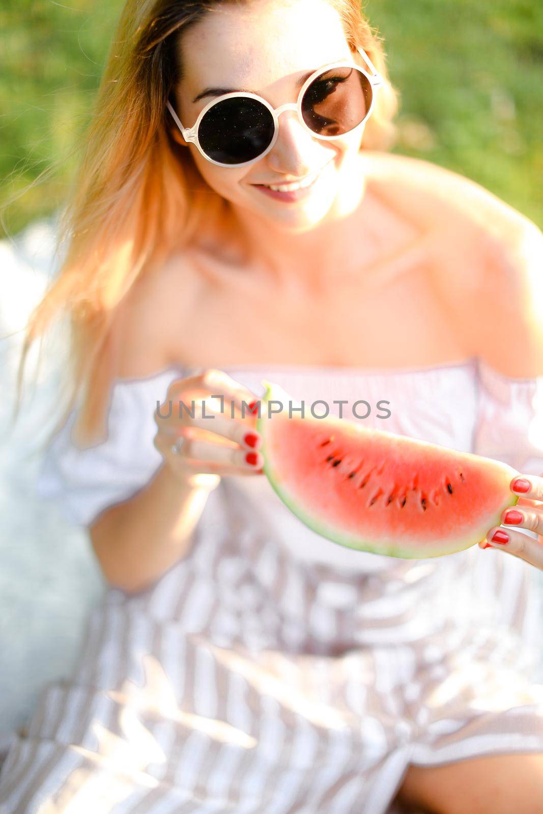 Young caucasian girl in sunglasses eating watermelon. Concept of healty food and summer season, vegeterian lifestyle.