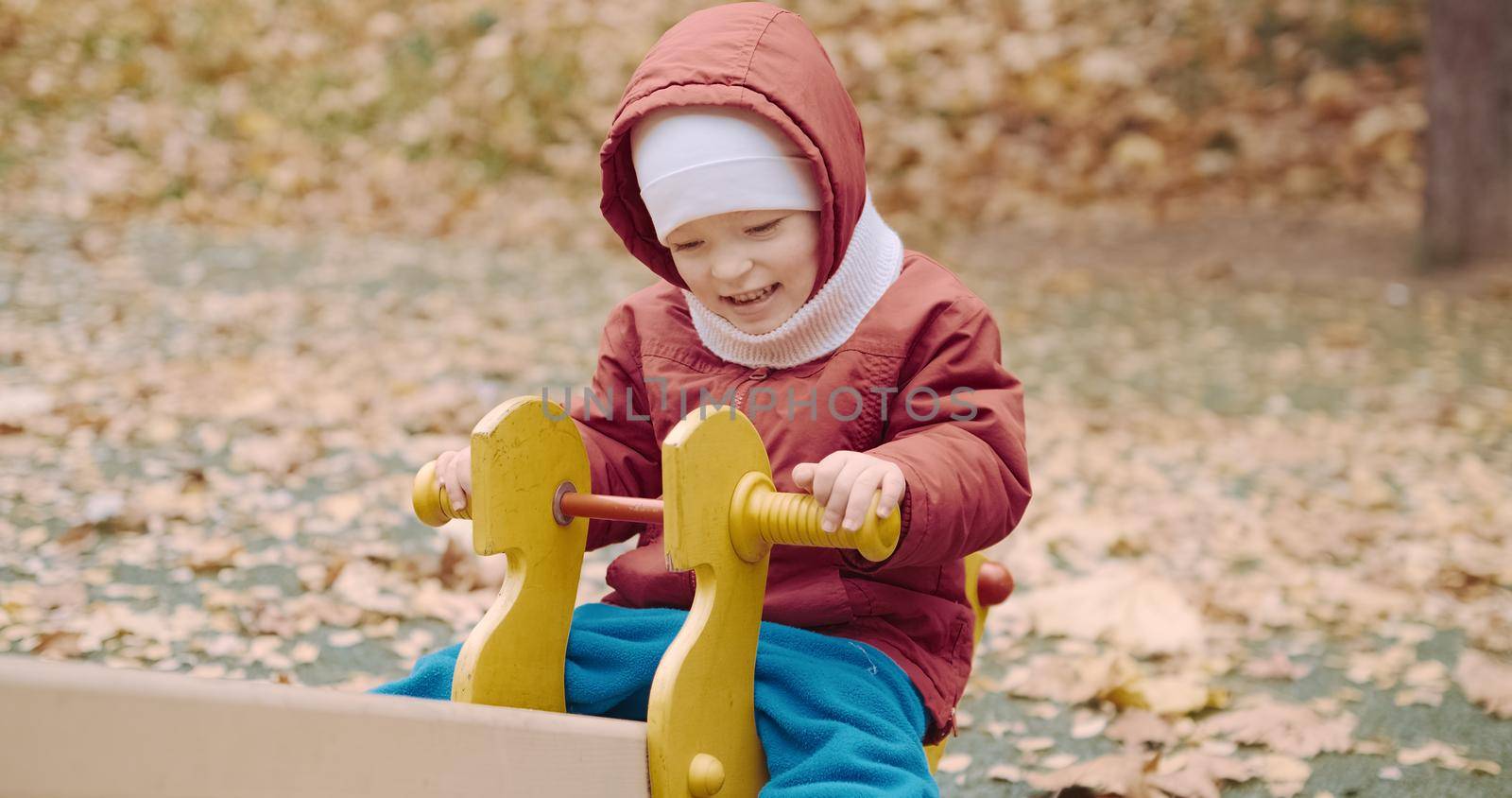Small, cute child rides on a swing in the yard on a walk. The carousel rolls the baby. Lifestyle and active recreation