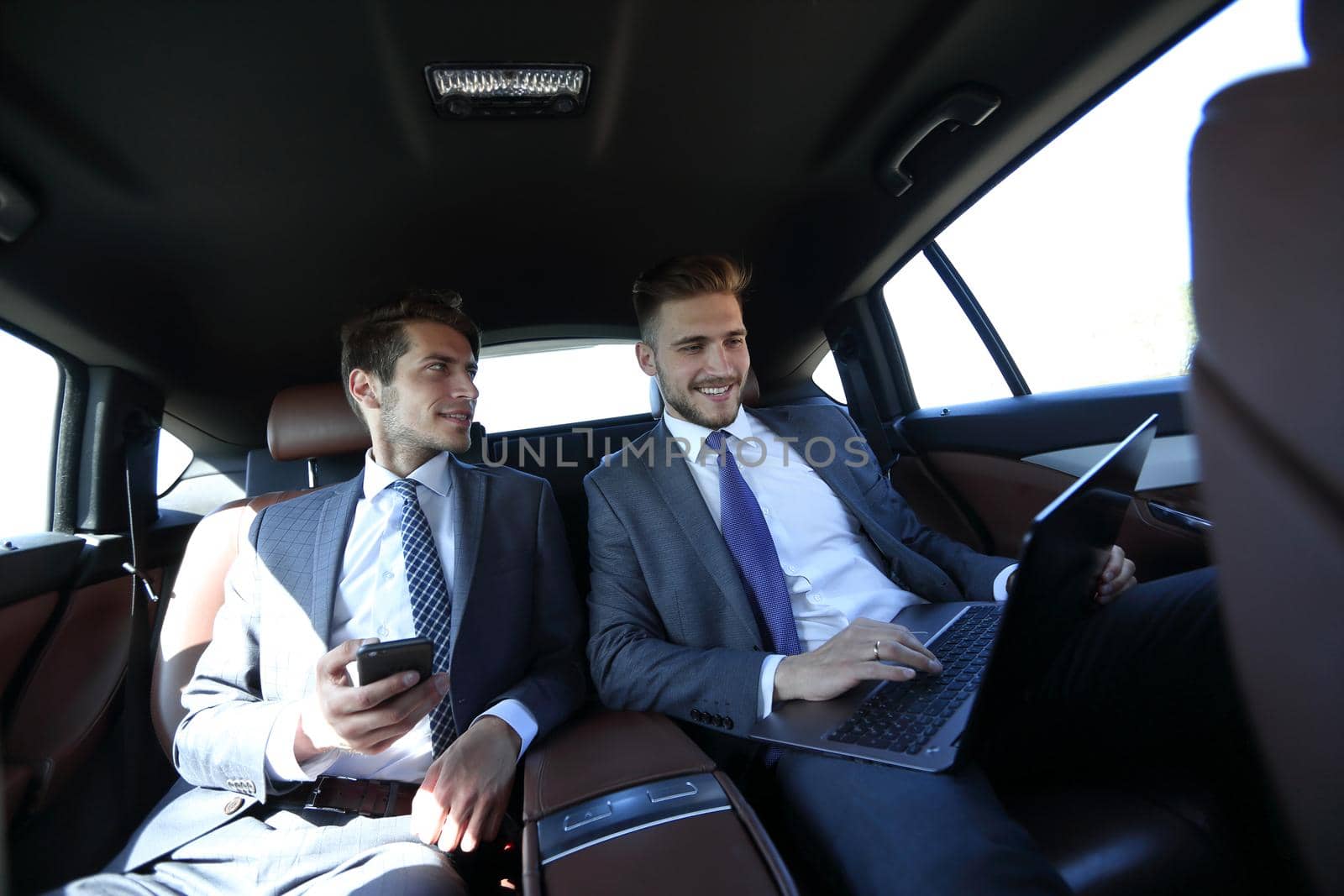 close up.business colleagues talking, sitting in the back seat of a car.business-trip