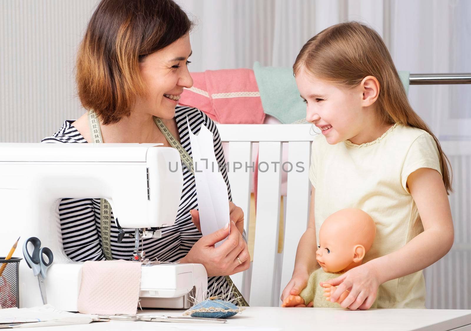 Woman showing to child how to sew at home by GekaSkr