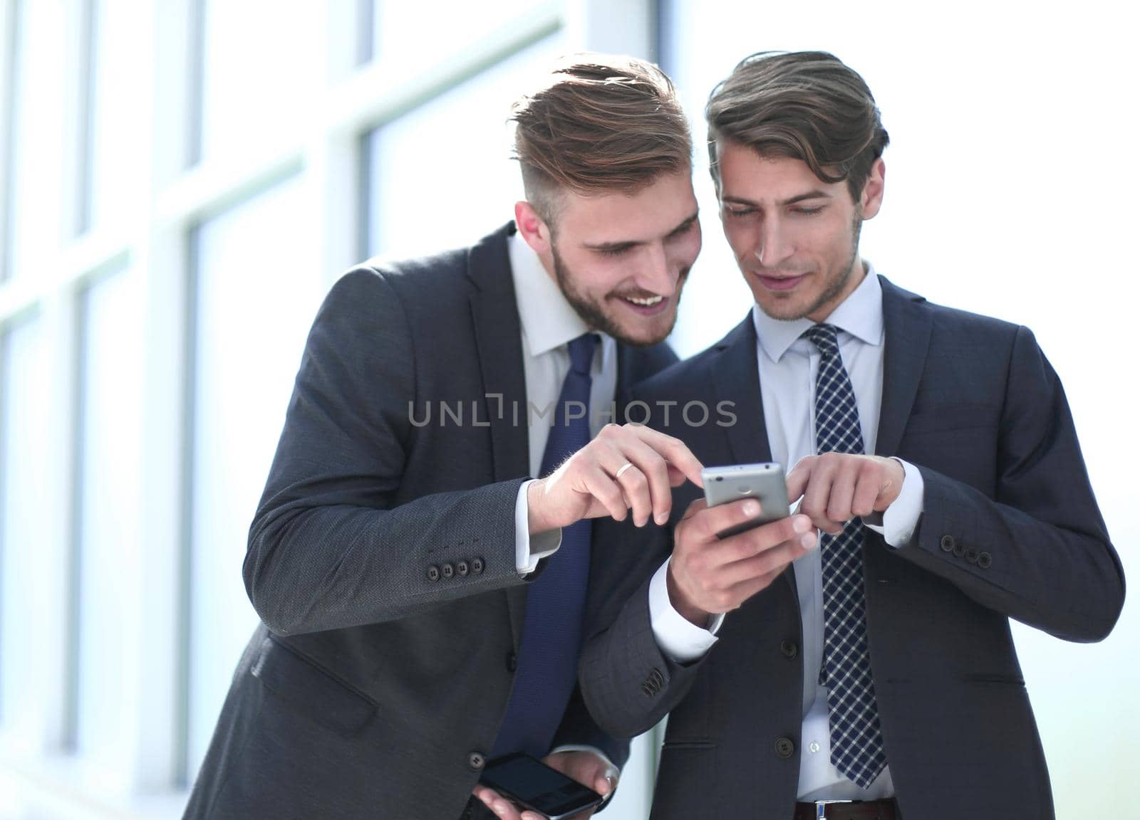 two employees discussing media files on their smartphones.people and technology