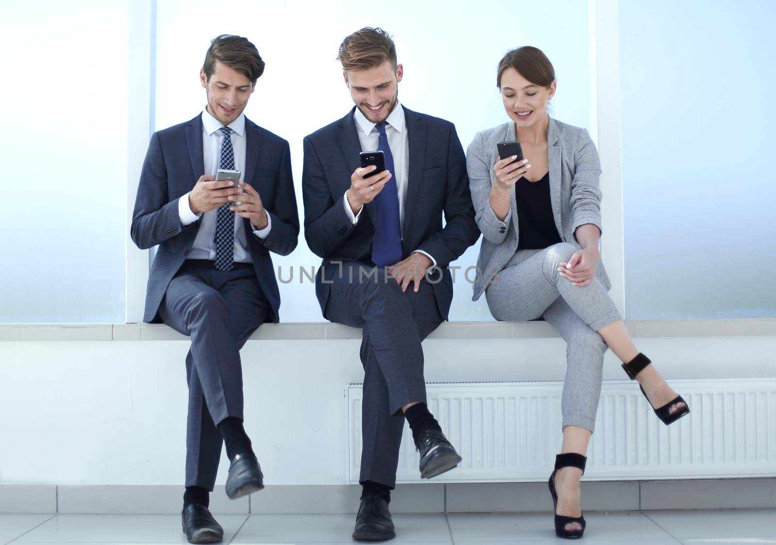 business team using their smartphones during work break. by asdf