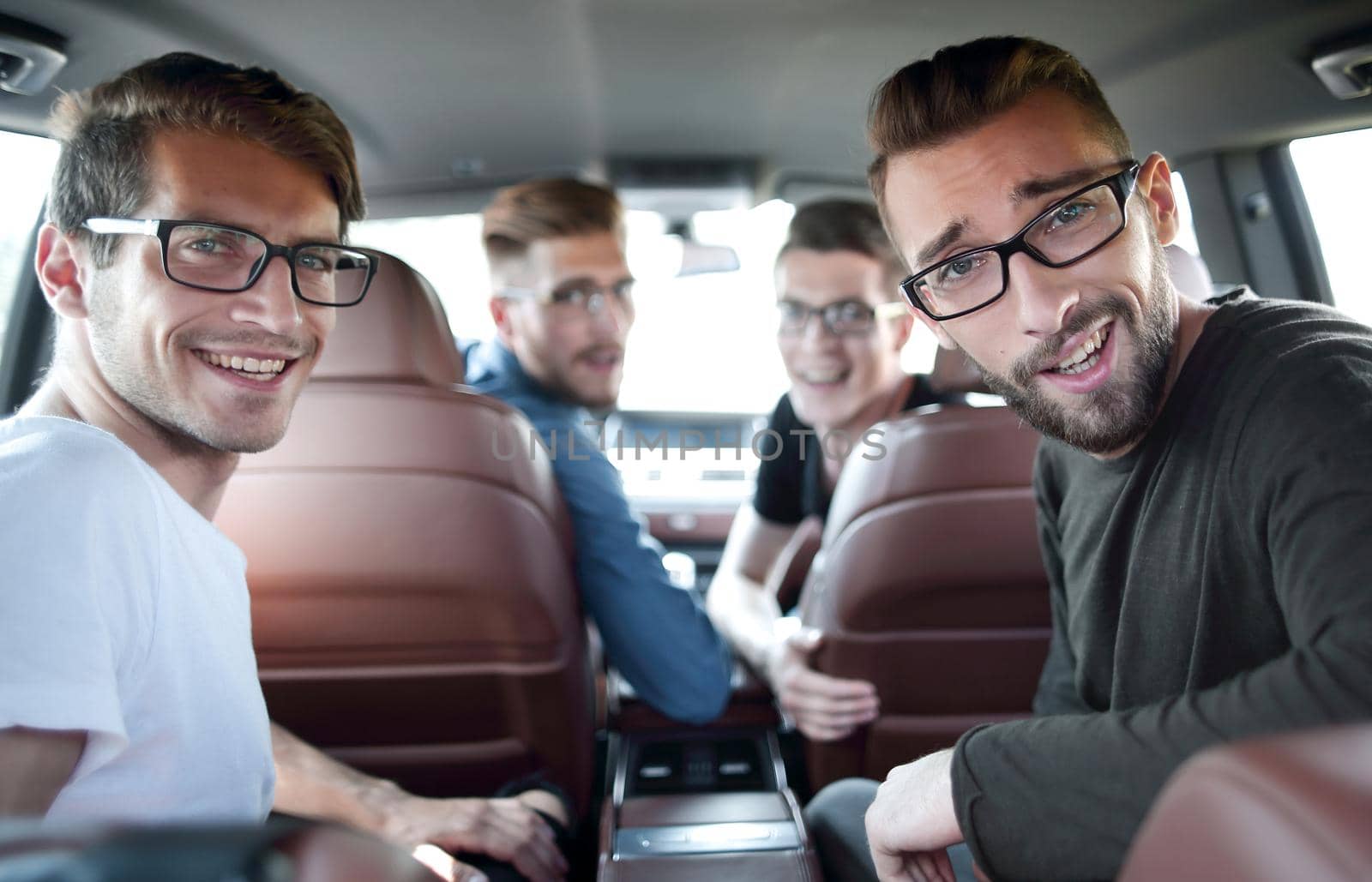 Handsome young man with friends in blue shirt driving car