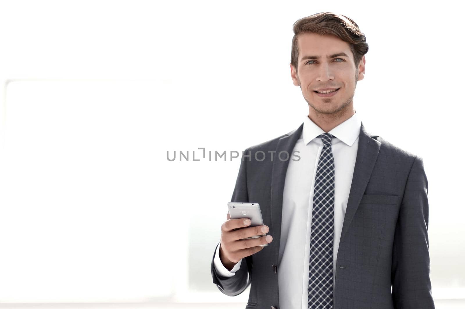 businessman with smartphone standing in a bright office.photo with copy space