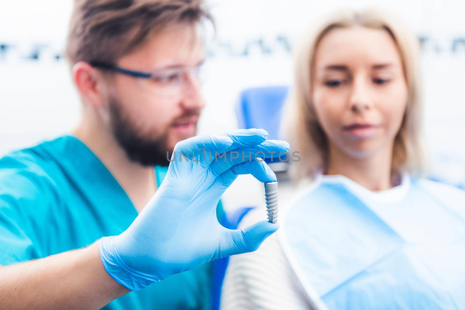 Dentist showing gray implant model to patient