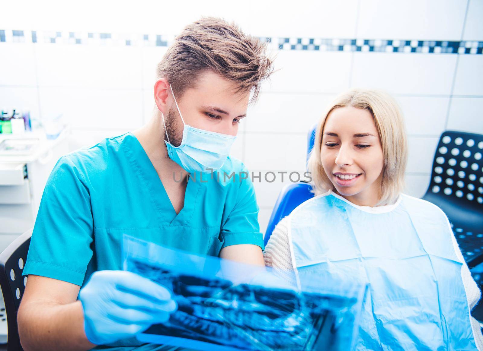 Dentist in mask showing patient dental x-ray