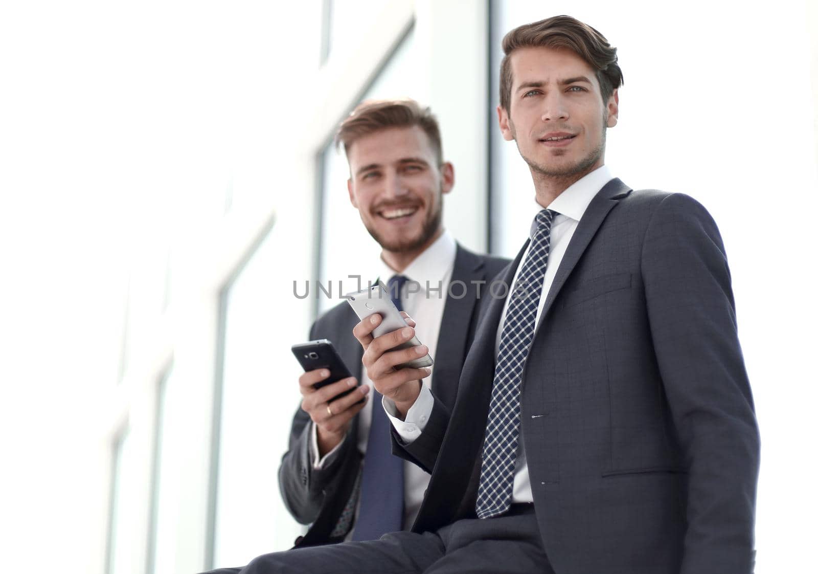 smiling business colleagues with smartphones sitting in the office lobby.photo with copy space