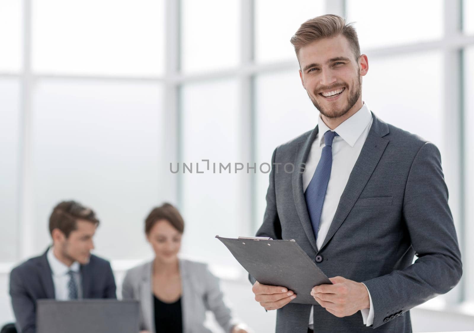 smiling businessman with a clipboard on the background of the office.photo with copy space