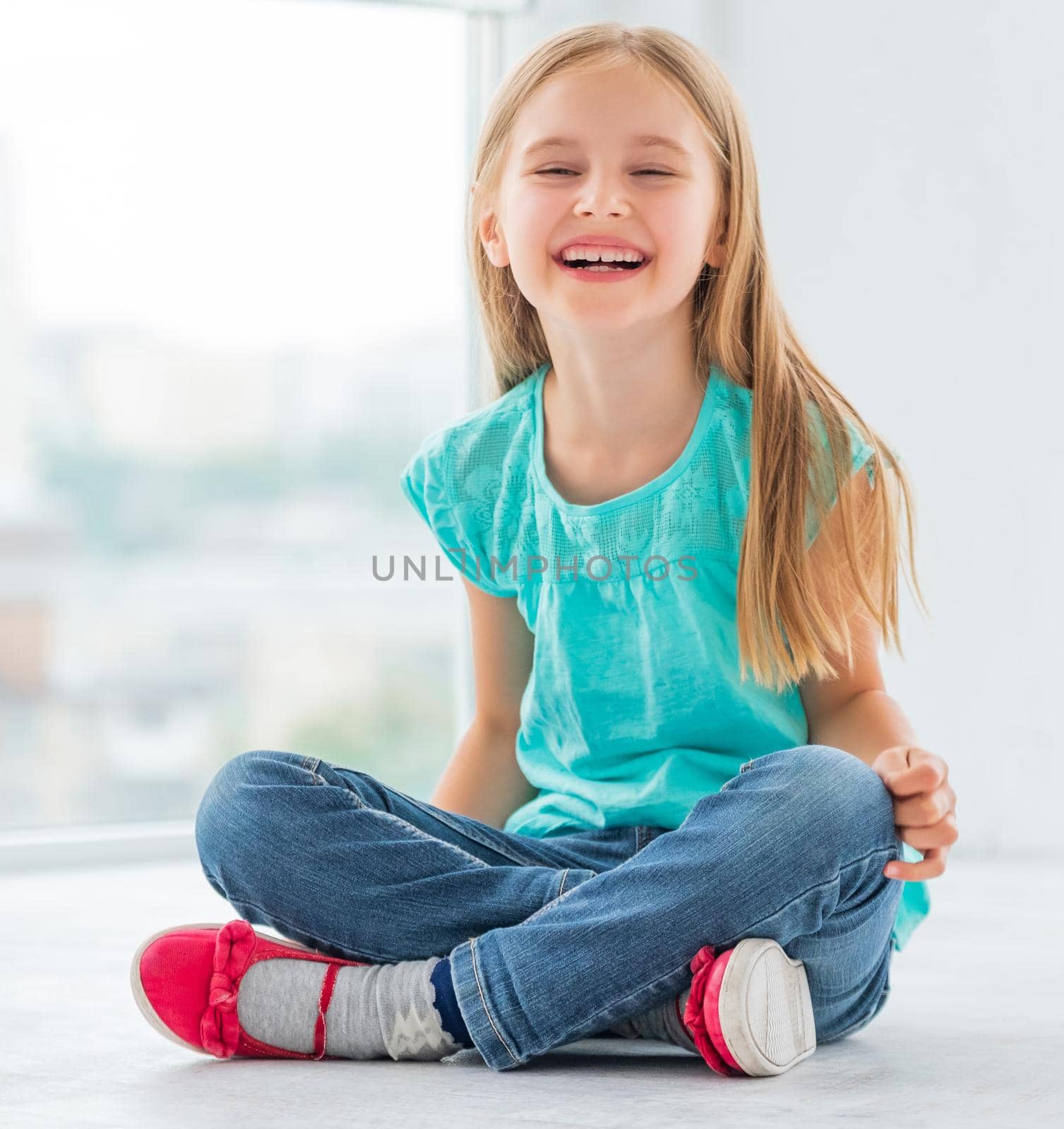 Funny school girl siting on floor ang having fun.