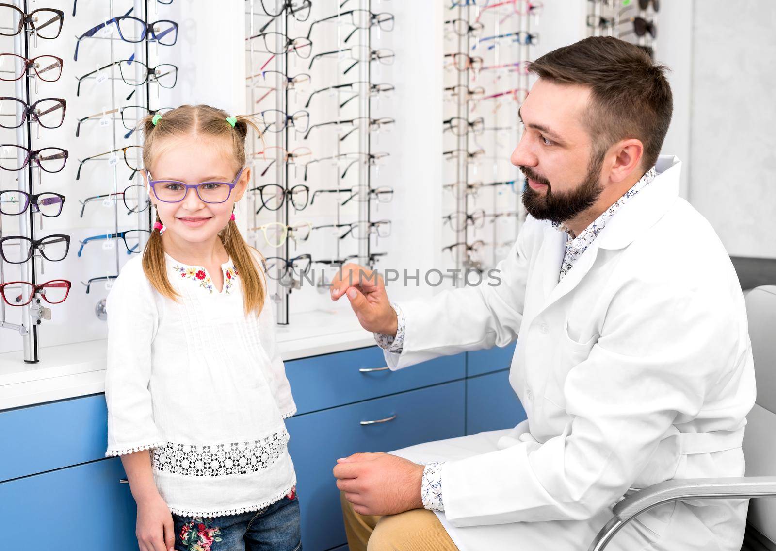 Little girl and doctor ophthalmologist choose glasses