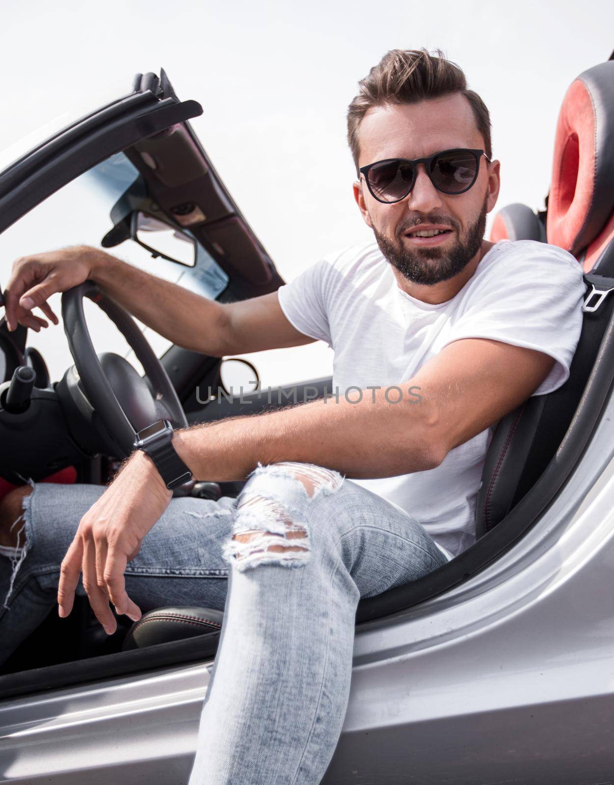 close up.stylish young man sitting in a luxury car .side view