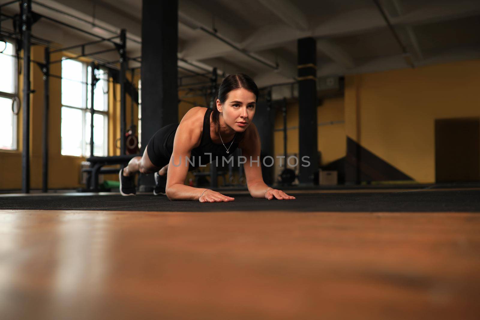 Portrait of a muscular woman on a plank position. by tsyhun