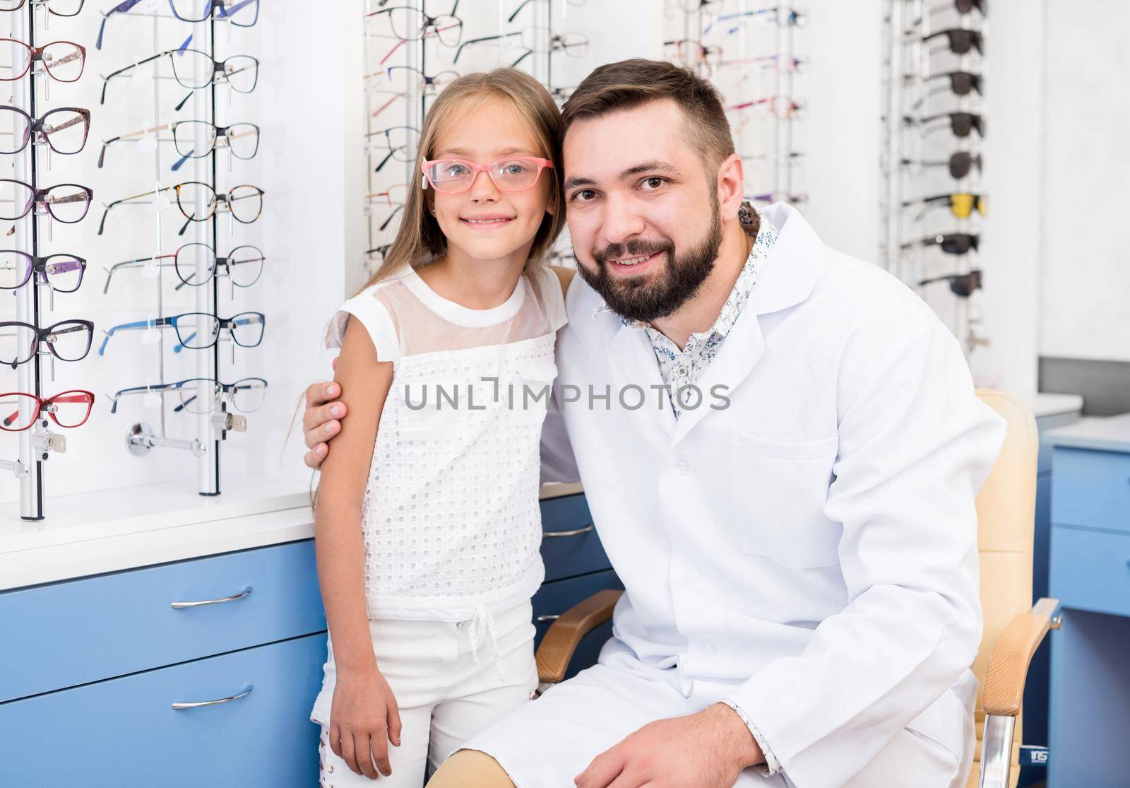 doctor chooses glasses for little girl in ophthalmologic clinic