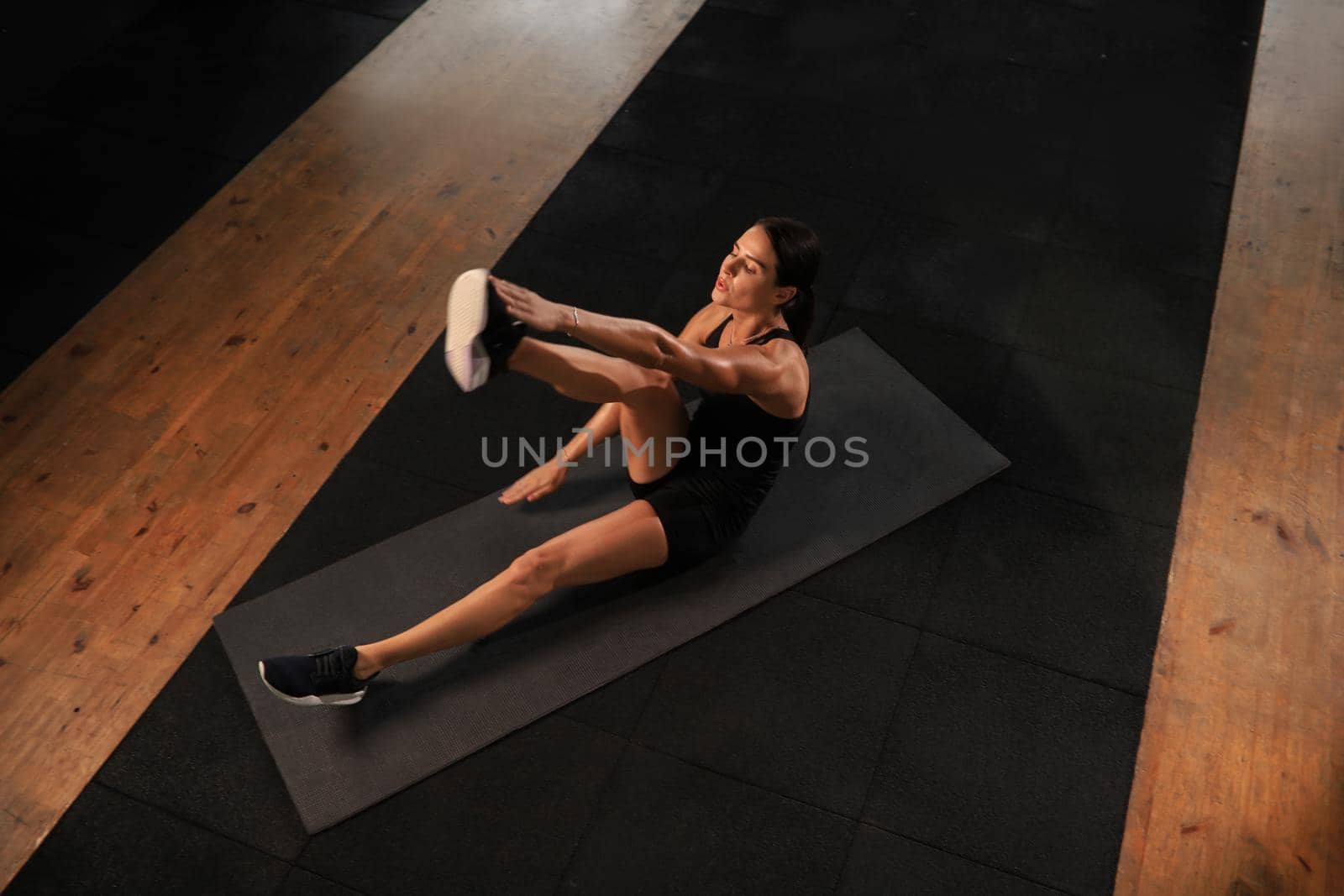 Young woman in sportswear doing crunches at the gym, top view