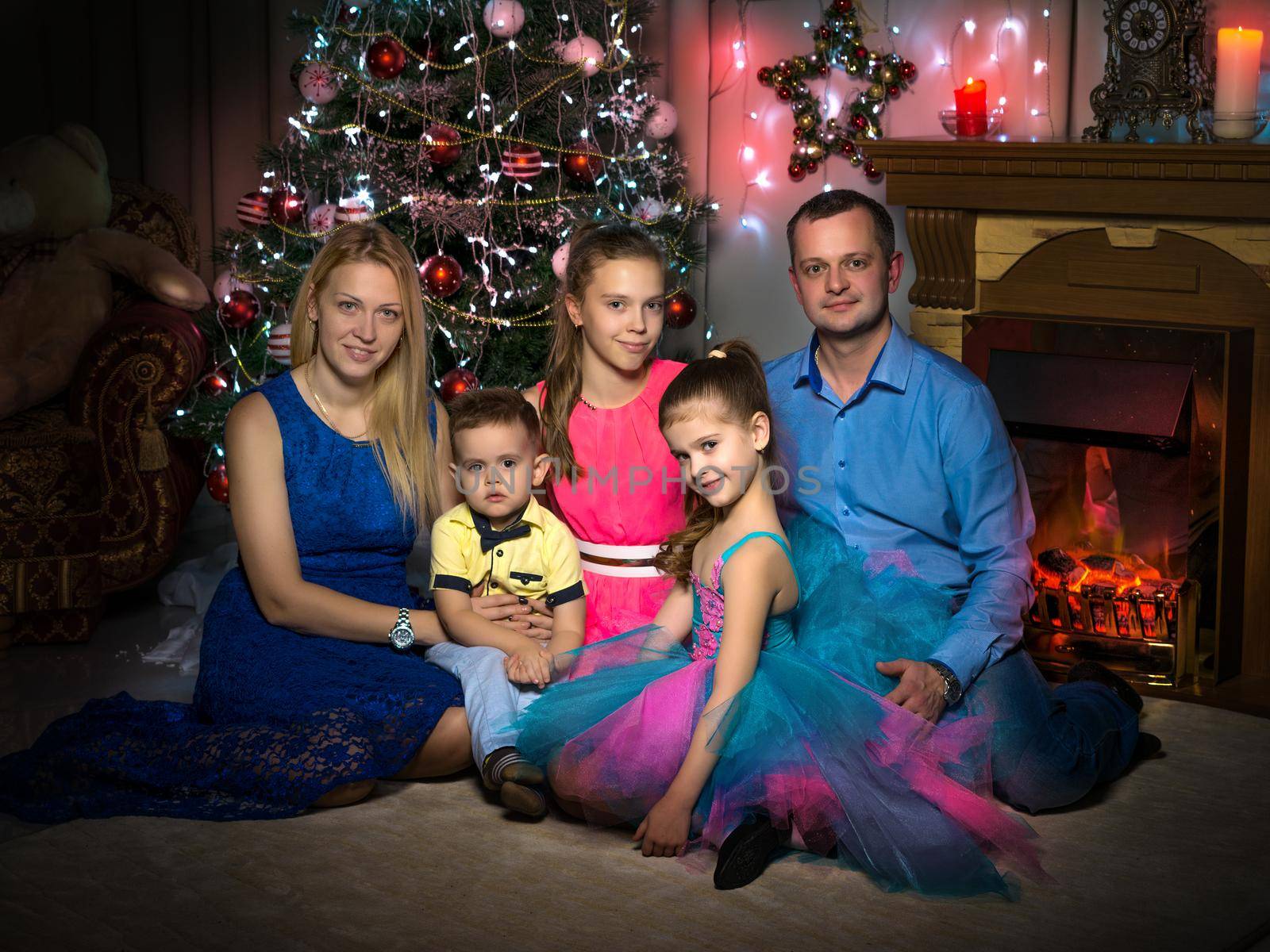 Happy young family with children at Christmas near a Christmas tree and a fireplace. The concept of holidays, winter, Christmas, Happy childhood, the harmonious development of children in the family.