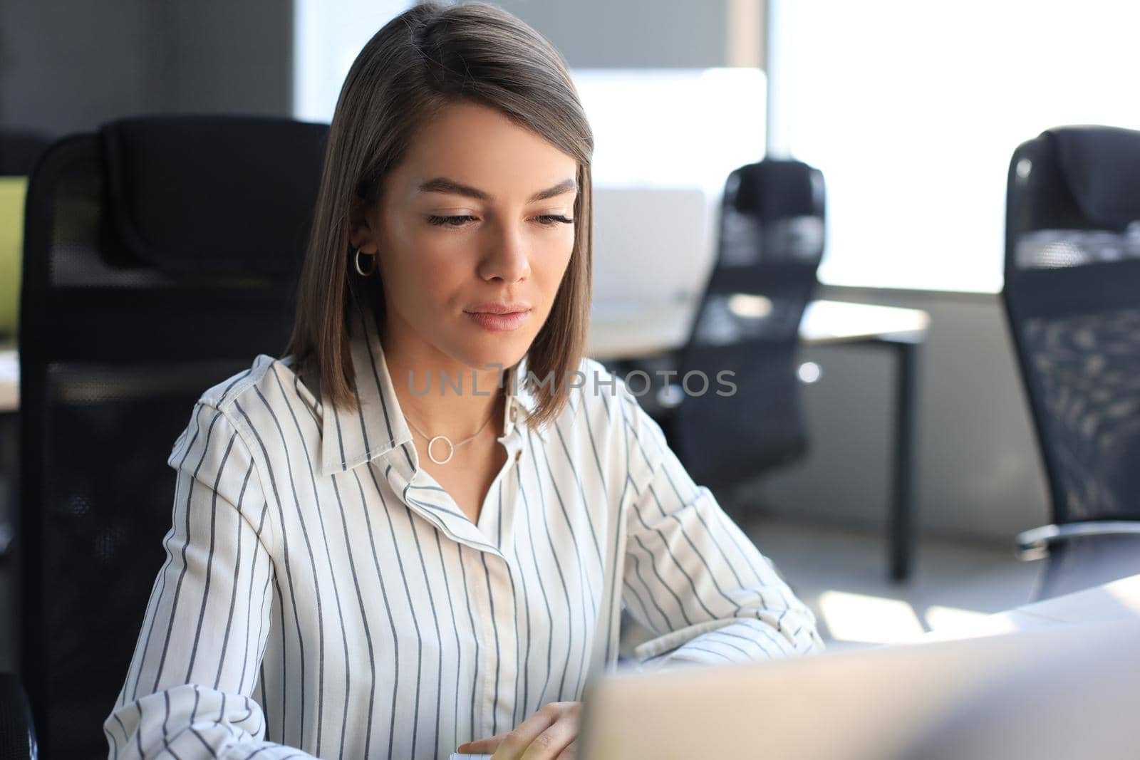 Beautiful business woman in smart casual wear working on laptop in the office.
