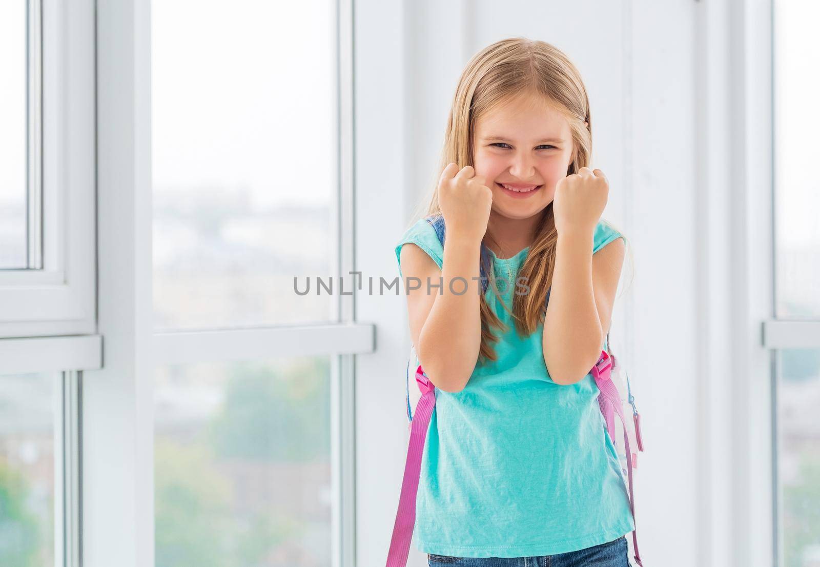 Young beatiful schoolgirl is so happy about her new year of education that she clenched her fists very strong