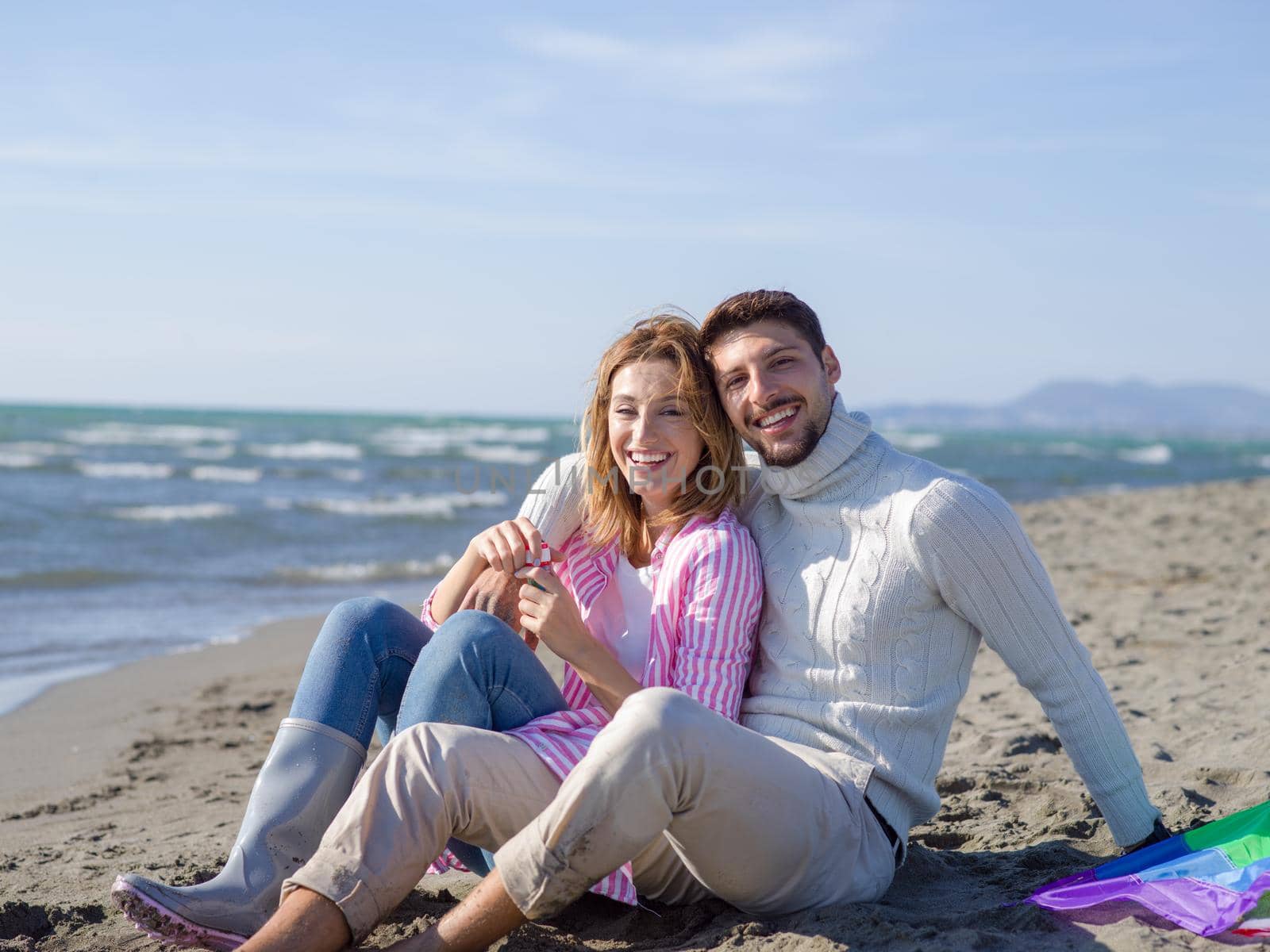 Young Couple having fun and making soap bubbles On The Beach at autumn day