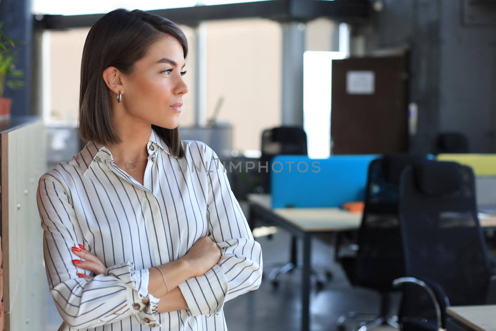 Attractive business woman in smart casual wear looking away while standing in the office by tsyhun
