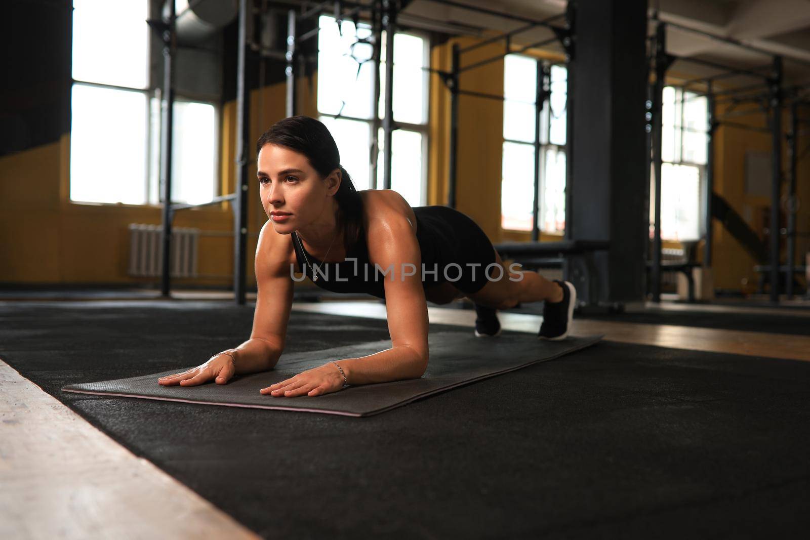 Portrait of a muscular woman on a plank position. by tsyhun