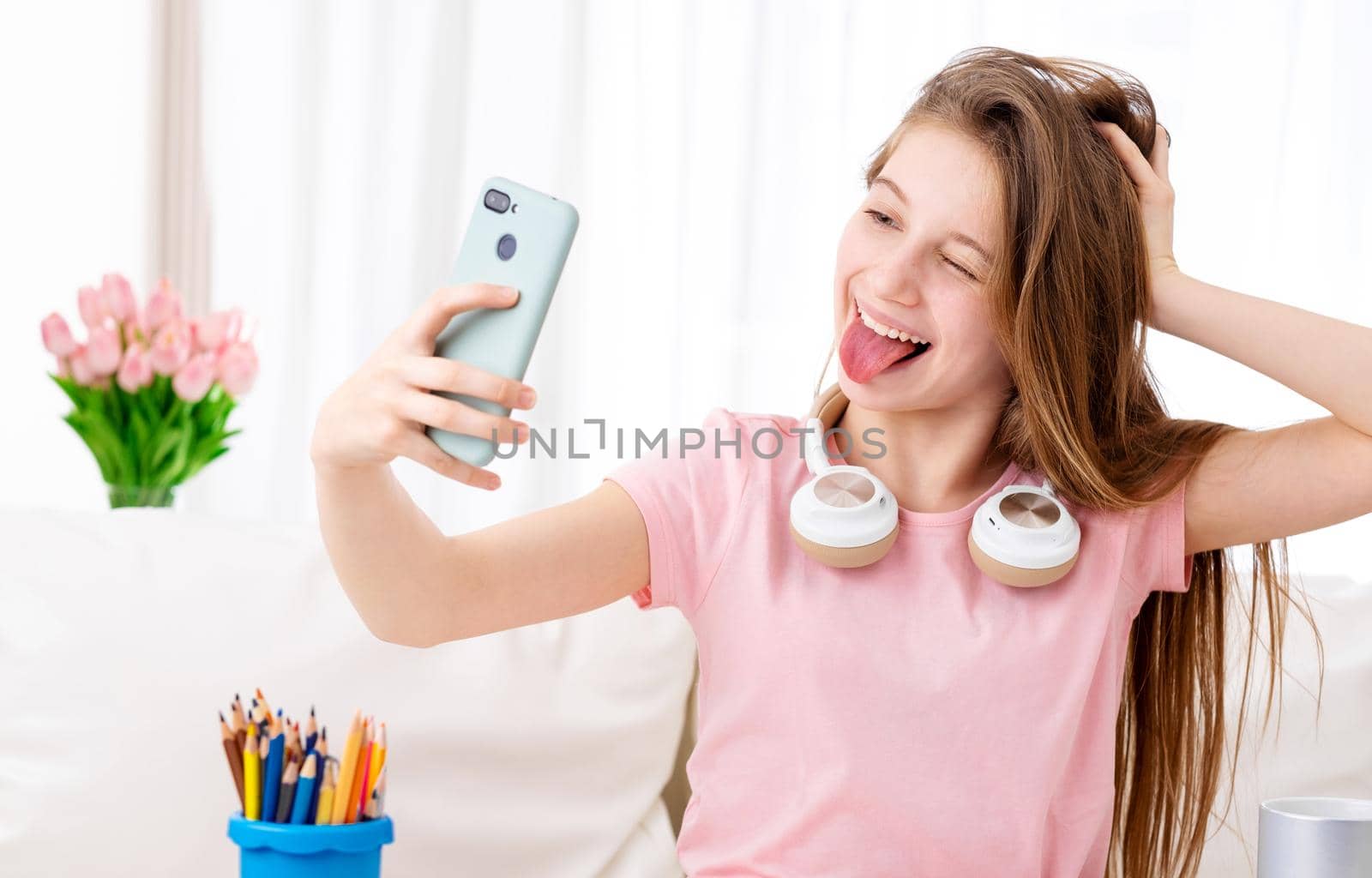 Beatiful teen making selfie of herself in cool headphones on breaks
