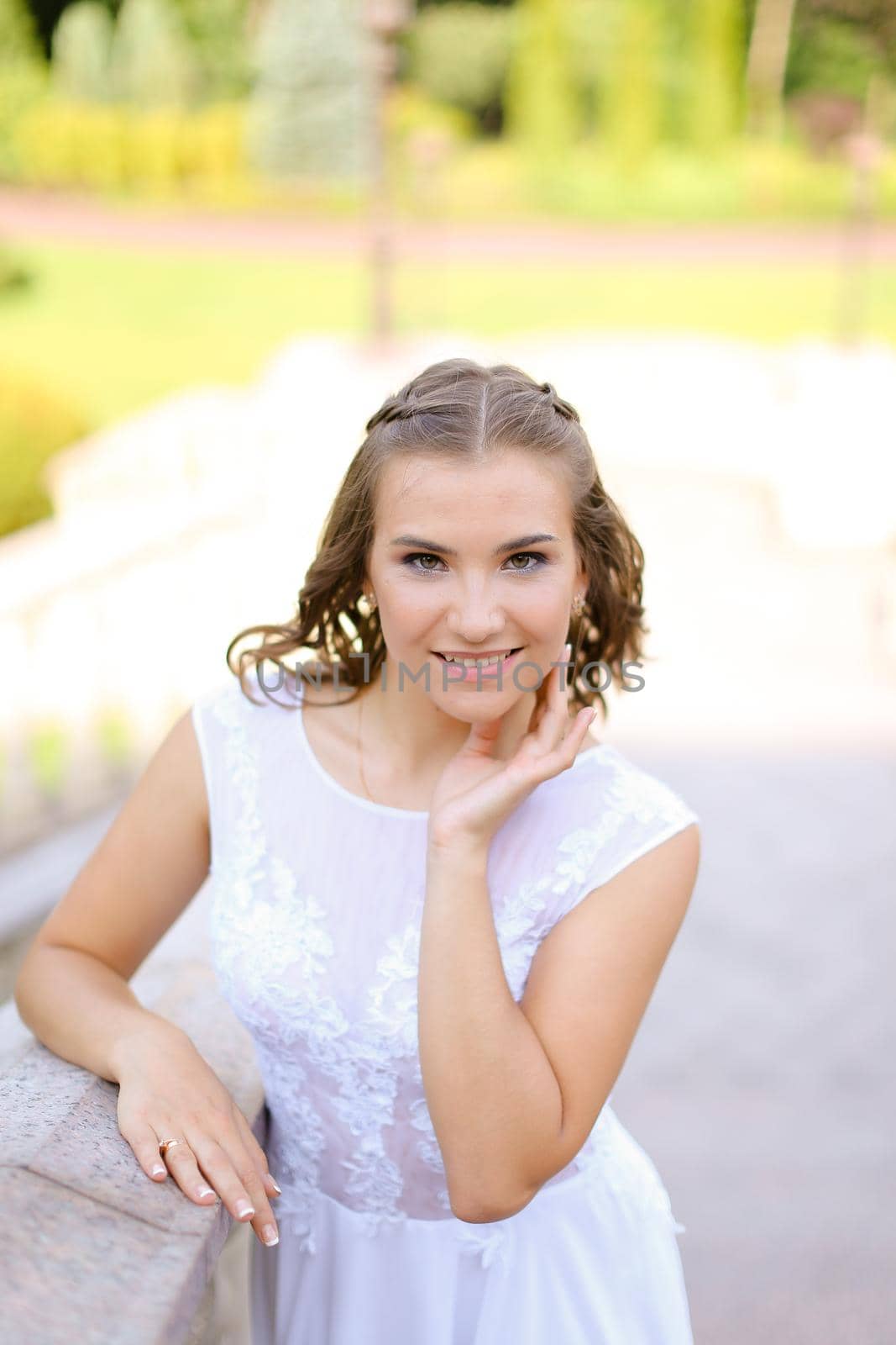 Happy charming bride wearing white dress standing outside and smiling. by sisterspro