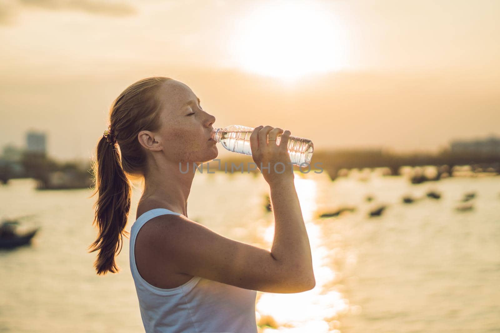 Sporty woman drinking water outdoor on sunny day.