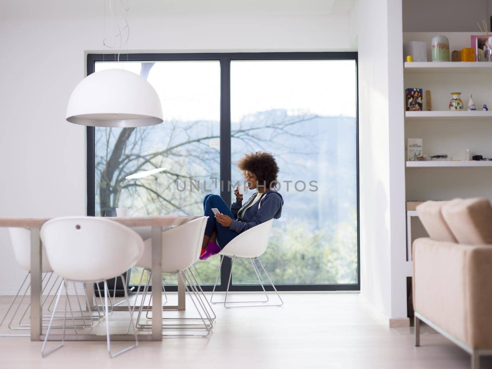 Handsome young african american woman drinking coffee and using a mobile phone at  home