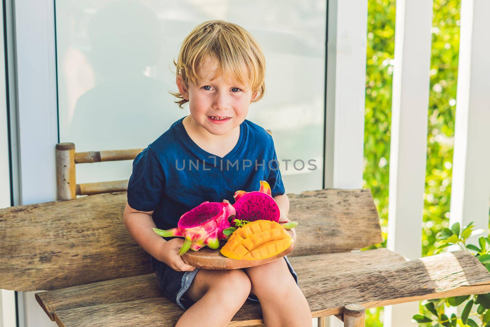 Diced dragon fruit and mango in the hands of the boy by galitskaya